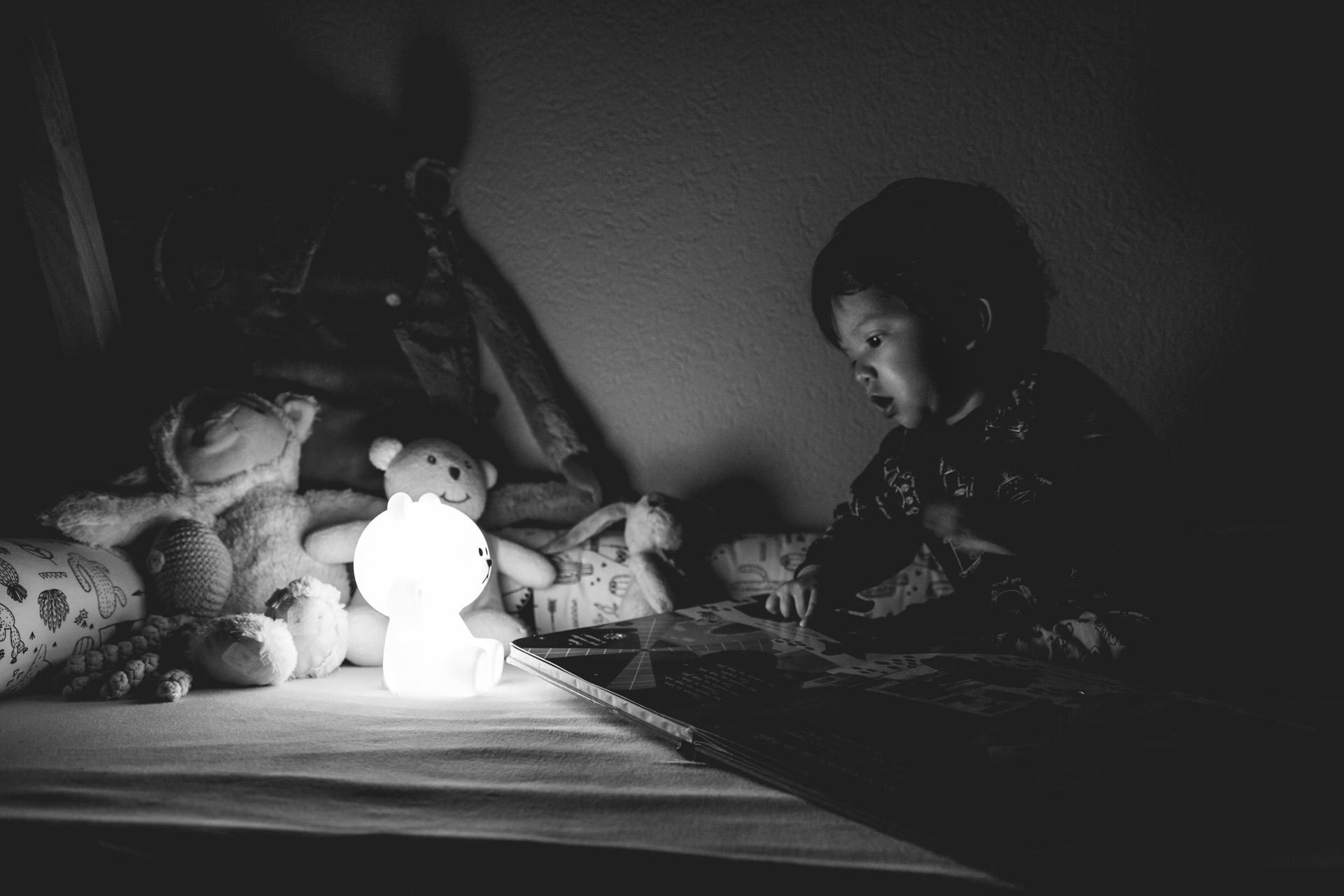 un enfant qui lit dans son lit avec une veilleuse à côté de lui